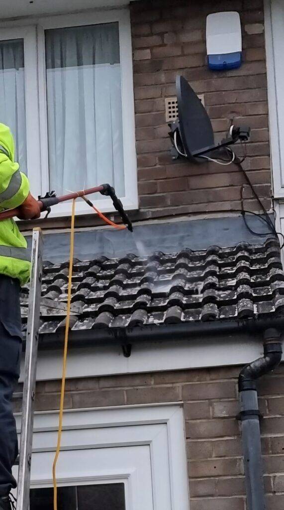 Technician applying biocide to a cleaned tiled roof in Bramley, Leeds, to prevent regrowth after roof cleaning.