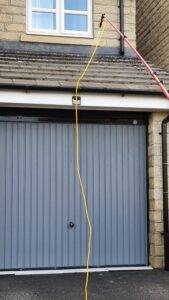 Biocide treatment applied after roof cleaning to prevent moss regrowth above a garage in West Yorkshire