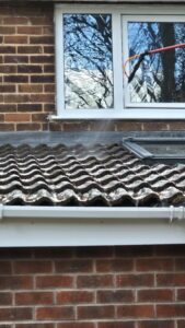 Biocide application during roof cleaning in Leeds showing treatment being sprayed onto concrete roof tiles after moss removal