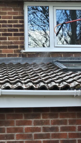 Biocide application during roof cleaning in Leeds showing treatment being sprayed onto concrete roof tiles after moss removal