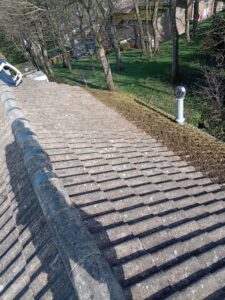 Roof cleaning in Leeds after manual moss removal showing cleaned concrete roof tiles and cleared moss from the roof edge