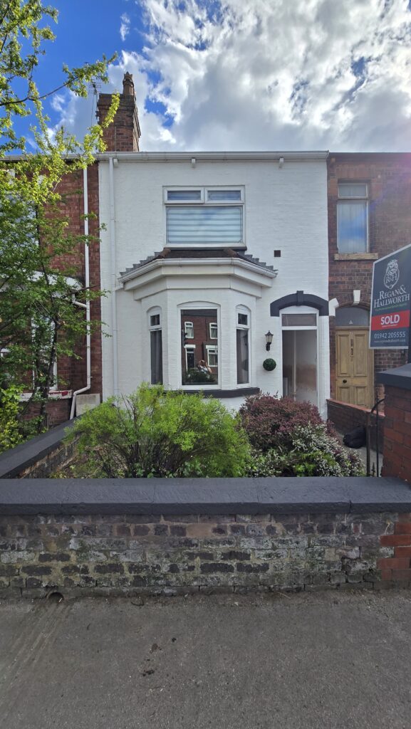 Finished house exterior in Greater Manchester after ivy removal, gutter repair and fresh white exterior painting.